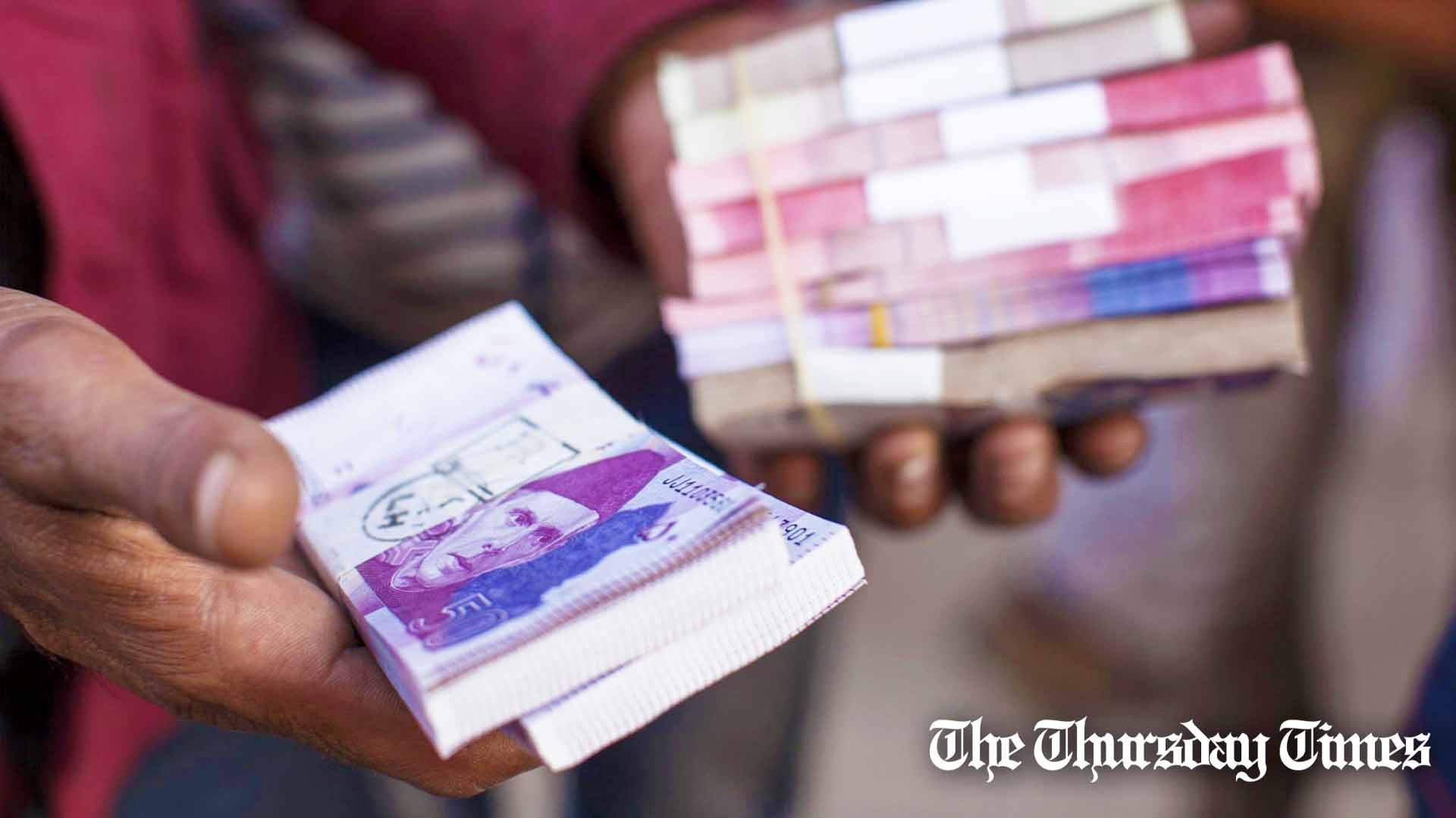 A forex agent handles Pakistani rupee banknotes at Karachi. — BLOOMBERG