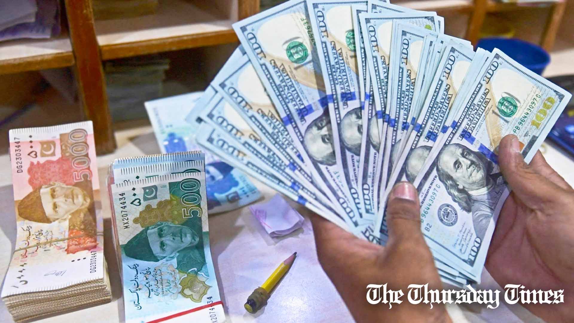 A forex dealer counts U.S. dollars at Karachi. — AFP