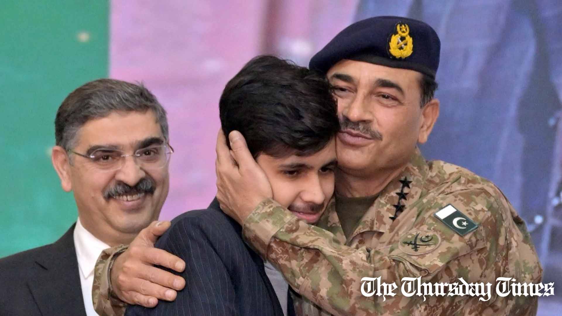 A file photo is shown of COAS General Asim Munir (R) embracing a student (C) as interim PM Anwaar-ul-Haq Kakar looks on (L). — ISPR